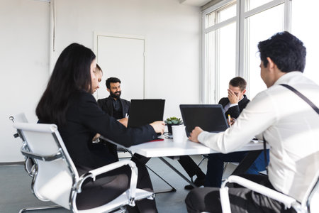 Group of young business people working and communicating while sitting at the office desk together...