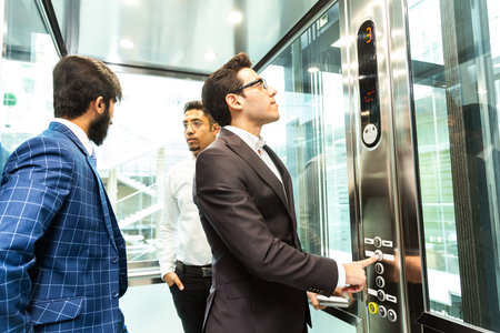 Business team group going on elevator. Business people in a large glass elevator in a modern office....