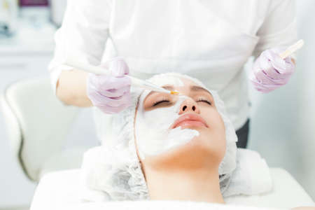 Facial skin care and protection. A young woman at a beauticians appointment. The specialist applies...