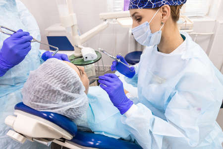 Dentistry concept. Professional dental services and modern equipment without pain. A doctor with an assistant treats the patients teeth and gives an anesthetic injectionの写真素材