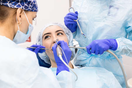 Dentistry concept. Professional dental services and modern equipment without pain. A doctor with an assistant treats the patients teeth and gives an anesthetic injectionの写真素材