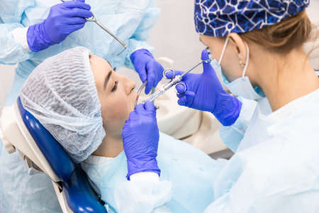 Dentistry concept. Professional dental services and modern equipment without pain. A doctor with an assistant treats the patients teeth and gives an anesthetic injectionの写真素材