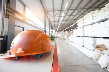 Protective orange hard hat close up on the background of industrial factory interiorsの写真素材