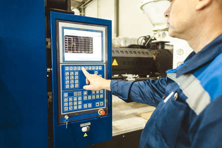 A worker presses a button and starts an automatic manufacturing process in a factory