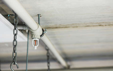 Close up image of fire sprinkler with fire in background. Fire sprinklers are part of an integrated water piping system designed for life and fire safety.の写真素材