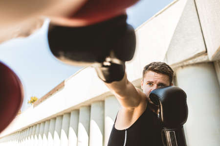 Two men exercising and fighting in outside. Boxer in gloves is training with a coachの写真素材