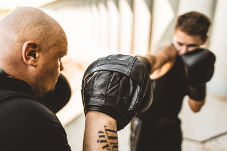 Two men exercising and fighting in outside. Boxer in gloves is training with a coachの写真素材