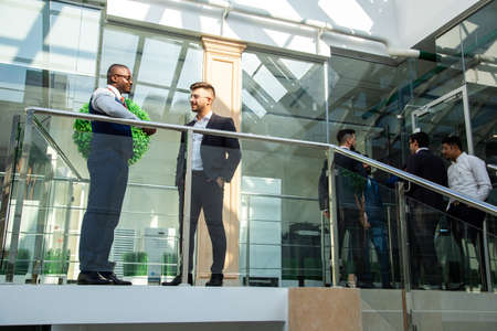 young business people are standing and talking on the background of glass offices. Corporate businessteam and manager in a meeting.の写真素材