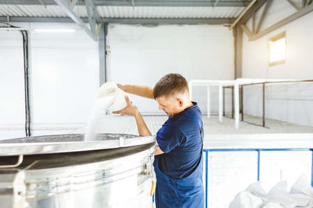 A worker in protective overalls performs a production process at an industrial factoryの写真素材