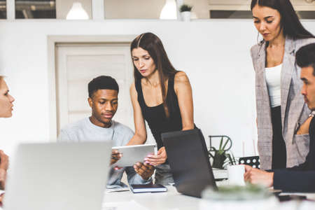 A team of young office workers, businessmen with laptop working at the table, communicating together in an office. Corporate businessteam and manager in a meeting. coworking.の写真素材