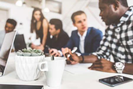 A team of young office workers, businessmen with laptop working at the table, communicating together in an office. Corporate businessteam and manager in a meeting. coworking.の写真素材