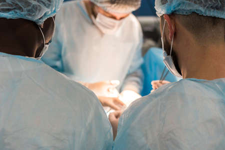 An international team of doctors performs a complex surgical operation on a patient under anesthesia. Modern operating room and experienced surgeons save livesの写真素材