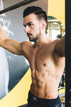Handsome young sporty male bodybuilder with naked torso posing in the gymの写真素材