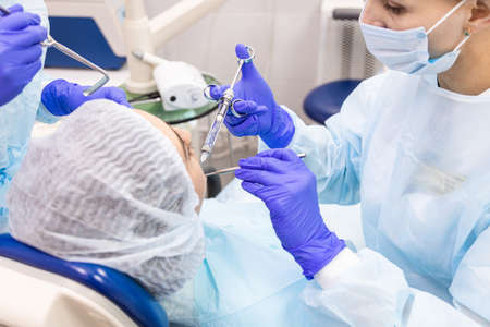 Dentistry concept. Professional dental services and modern equipment without pain. A doctor with an assistant treats the patients teeth and gives an anesthetic injectionの写真素材