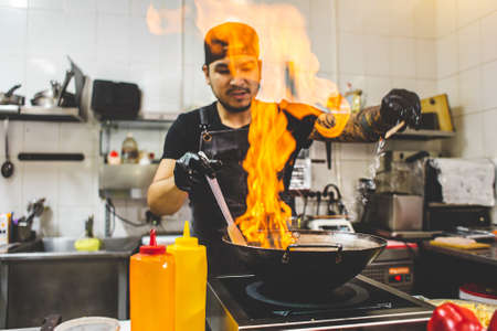 street food. fried noodles in a wok with chicken and shrimp on the open fireの写真素材