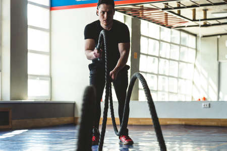 Crossfit with ropes. The athlete is training in the gym opposite large panoramic windowsの写真素材