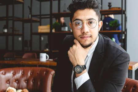 Portrait of a young successful businessman in a suit in the office. Close-up sitting in a chair by the windowの写真素材