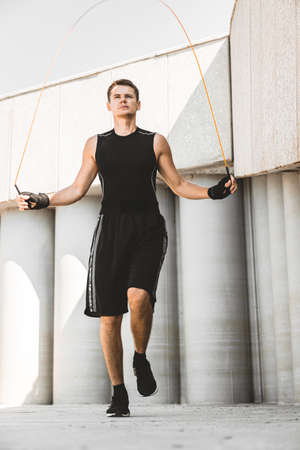 caucasian man fighter training hard in the outdoors.. Man using rope, making warm up. concept about...