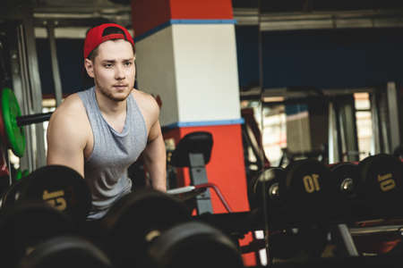 Portrait of a muscular man performs exercises in the gym. Strength training with dumbbells