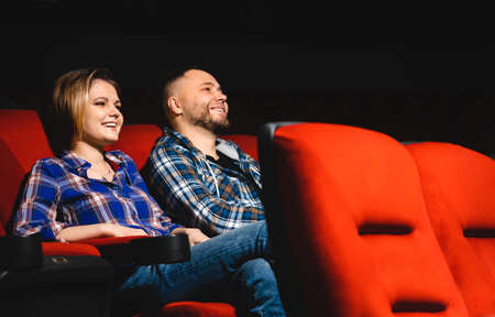 Friends are watching a movie in the cinema. People sit in the armchairs of the cinema and look at the screenの写真素材