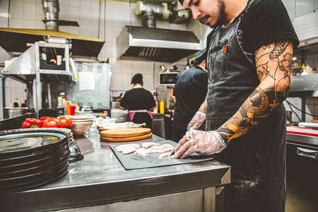 a chef in a restaurant cuts fish for making sushiの写真素材