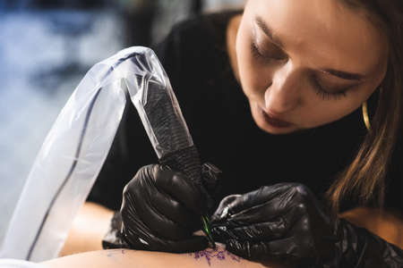drawing of a tattoo on the leg close-up. Woman tattoo artist makes a drawing with a special machine...