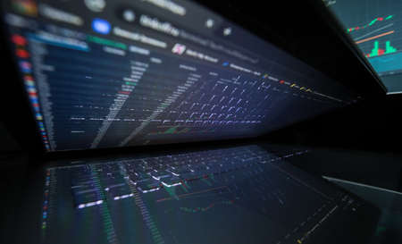 Laptop screen with stock market charts. Technical analysis and fundamental indicators of stock quotes in the trading terminal. Japanese candlesticks and company tickers.の写真素材
