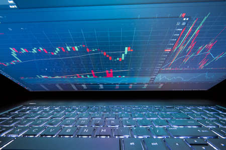 Laptop screen with stock market charts. Technical analysis and fundamental indicators of stock quotes in the trading terminal. Japanese candlesticks and company tickers.の写真素材