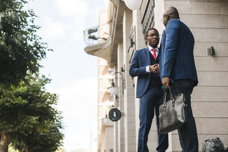 Portrait of two black African American businessman in suits shake hands outdoors. The joy of meeting...