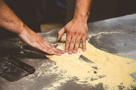 Professional chef cooking in the kitchen restaurant at the hotel, preparing dinner. A cook in an apron makes a pizza.の写真素材