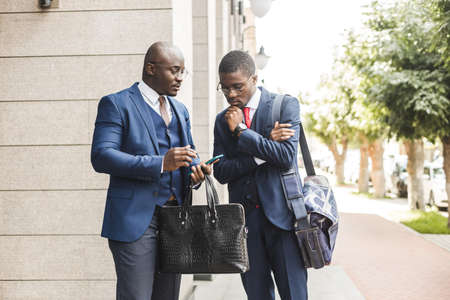 Portrait of two black African American businessman in suits exchanging business cards and contacts outdoors.の写真素材