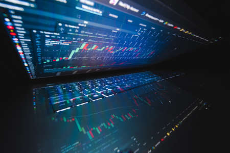 Laptop screen with stock market charts. Technical analysis and fundamental indicators of stock quotes in the trading terminal. Japanese candlesticks and company tickers.の写真素材