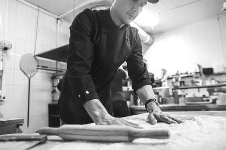 Professional chef cooking in the kitchen restaurant at the hotel, preparing dinner. A cook in an...