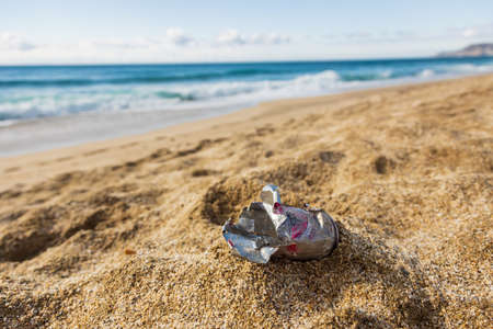 Pollution of the planet with human waste. An empty tin can thrown away by the sea on the beach....