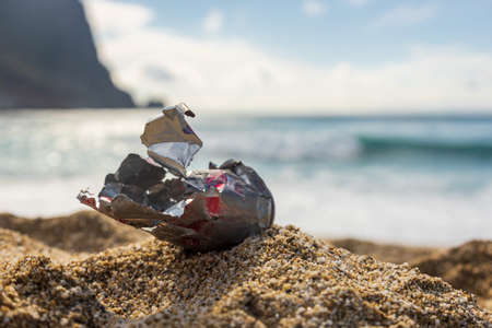 An old tin can washed up by the sea on a sandy shore. Mankind pollutes natureの写真素材
