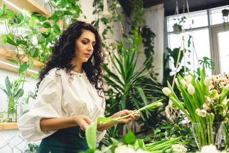 Attractive young woman florist is working in a flower shop.の写真素材