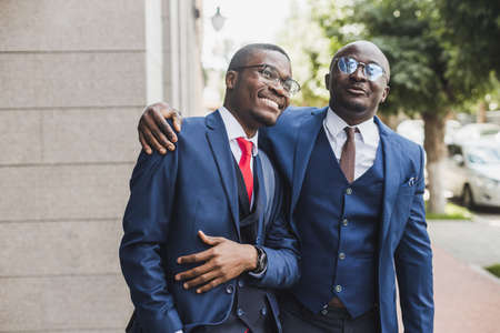 Meeting of two long-time friends of black African American businessman in suits outdoorsの写真素材