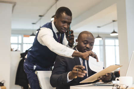 Two African American business partners are working on a laptop together on a common project. Coworking, social contacts and remote networkingの写真素材