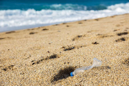 Garbage pollution of the planet. Empty plastic bottle on the beach sand. Consequences of human lifeの写真素材