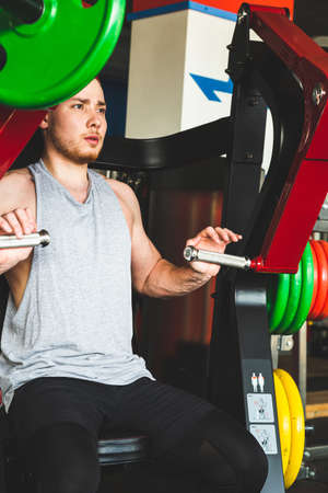 The young athlete does exercises in the gym. Power approaches on the simulatorの写真素材