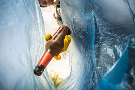 Close-up of a woman hand throwing garbage into a plastic bag. View from inside the bag. The concept...
