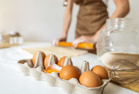 A woman in an apron prepares dough for baking at home. Rolling out and preparing dough for baking.