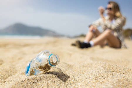 Close-up of a used discarded plastic bottle lying on the sand on the beach. Plastic environmental pollution with garbageの写真素材