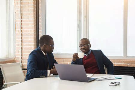 Two African American business partners are working on a laptop together on a joint project. Mutual assistance and establishment of social contactsの写真素材
