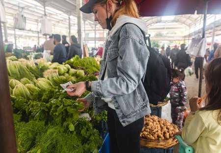 Buying fresh organic produce at the farmers market. A woman chooses fresh herbs, vegetables and...