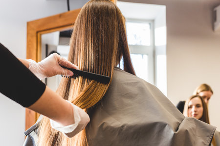 Close-up hairdresser combs the girls hair by styling in a beauty salon.の写真素材