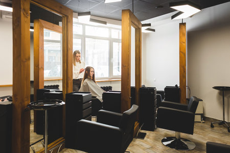 Hairdresser combs the girls hair by styling in a beauty salon.の写真素材