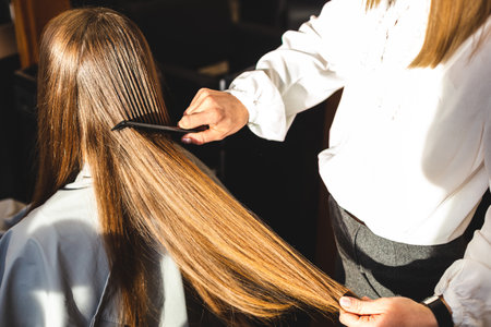 Close-up hairdresser combs the girls hair by styling in a beauty salon.の写真素材