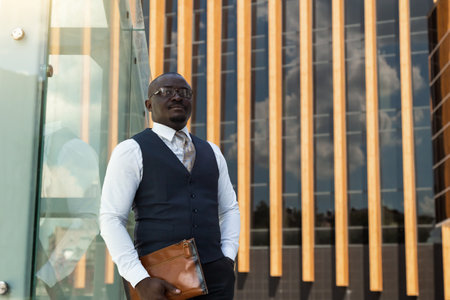 Portrait of an afro american businessman in a suit on the background of a modern building exteriorの写真素材