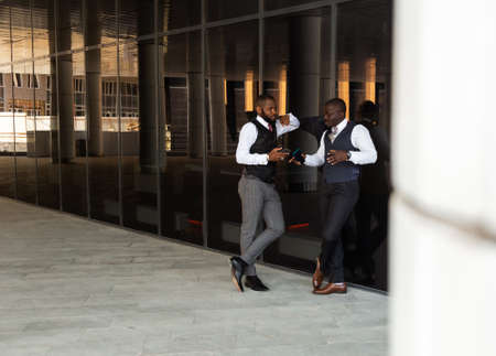 Portrait of two handsome african american businessman partner friends in suit against modern building exteriorの写真素材